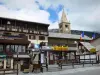 Montgenèvre - Ski resort (winter and summer sports resort): bell tower of the Saint-Maurice church with its headlight, chalet, French flags and shops