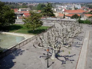 Montpellier - Peyrou district: square decorated with trees, lawns and lampposts with view of the roofs of the city