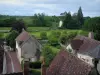 Montrésor - Toits des maisons du village, rivière (l'Indrois), prairies, arbres et ciel nuageux