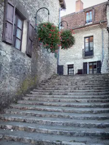 Morestel - Treppe, hängende Geranien  (Blumen) und Häuserfassaden aus Stein der Altstadt