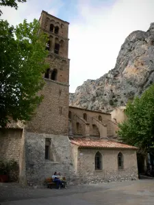 Moustiers-Sainte-Marie - Église Notre-Dame-de-l'Assomption et son clocher, arbres et falaise