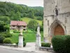 Mouthier-Haute-Pierre - Portail de l'église Saint-Laurent, parvis, statues de sainte Jeanne d'Arc et de saint Vernier, maison, prairies et arbres