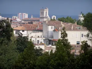 Nîmes - Vista de la torre del campanario de Notre-Dame y San Castor, casas y edificios de la ciudad, los árboles en primer plano