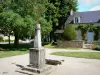 Nohant - Calvary (cross) on the church square and houses of the village; in the town of Nohant-Vic