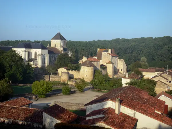 Nouaillé-Maupertuis abbey - Saint-Junien abbey (ancient Benedictine abbey) with the abbey church, the convent buildings, the surrounding wall and the towers; trees, roofs of houses of the village in foreground