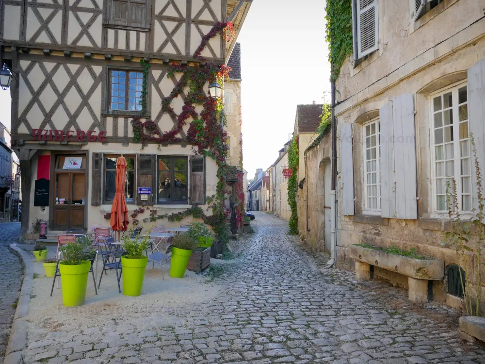 Noyers-sur-Serein - Noyers: Façades de maisons anciennes, terrasse de café et ruelles pavées de la cité médiévale