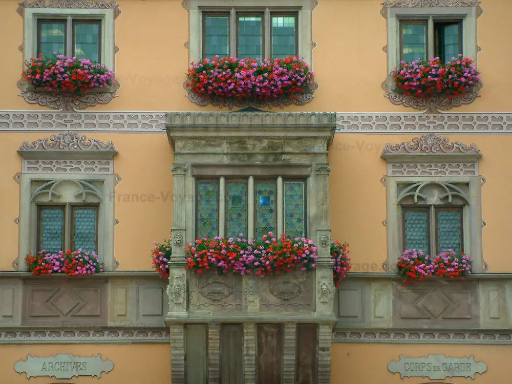 Obernai - Façade colorée de l'hôtel de ville (mairie) avec oriel et fenêtres ornées de fleurs (géraniums)