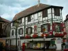 Obernai - Witte vakwerkhuis ingericht met schilderijen en versierd met bloemen (geraniums), restaurant met terras en winkel