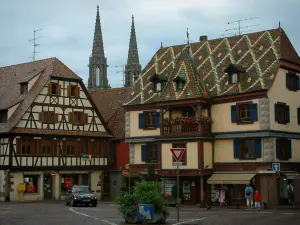 Obernai - House with glazed tiles on the roof, half-timbered residence and Saints-Pierre-et-Paul church in background