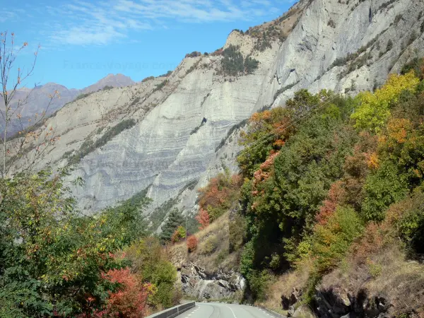 Oisans - Carretera bordeada de árboles y montañas, en los colores del otoño