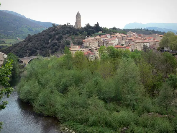 Olargues - Klokkentoren met uitzicht op de huizen van het dorp brug over de rivier en de bomen Jaur water, heuvels op de achtergrond, in het Regionale Natuurpark van de Haut Languedoc