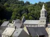 Orcival basilica - Octagonal belfry of the Romanesque Basilica Notre-Dame, roofs of houses and trees; in the Auvergne Volcanic Regional Nature Park, in the Monts Dore mountain area 