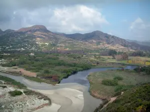 Ostriconi valley - River (streaming to the sea) surrounded by trees, with vegetation, hills and mountains