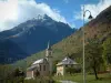 Paisajes alpinos de Saboya - Lámpara de pie, la iglesia y las casas de una aldea, el bosque de otoño, las montañas y las nubes en el cielo