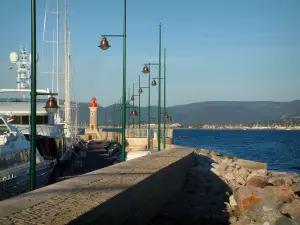 Paisajes del litoral de la Costa Azul - Pier, farolas, faros, yates y veleros en el puerto de Saint-Tropez, mar Mediterráneo y las colinas de las montañas de Maures, en el fondo