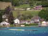 Paladru lake - Natural lake of glacial origin, moored paddle boats, bank, houses, fields and trees