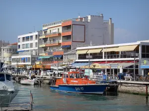 Palavas-les-Flots - Canal with moored boats, quay, shops, houses and buildings of the seaside resort