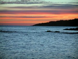 Paysages du littoral de la Côte d'Azur - Ciel rouge avec des nuages gris au lever du soleil, côte, rochers (écueils) et mer méditerranée