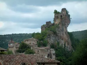 Penne - Dach eines Hauses vorne, und Ruinen des Schlosses (Festung) hochgestellt auf einen felsigen Sporn, dominieren die Häuser des Dorfes (albigeoise Bastide), die Bäume und den Wald, bewölkter Himmel