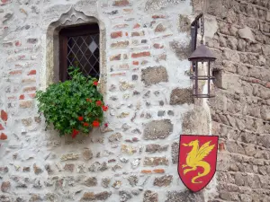 Pérouges - Steinfassade mit Wappen von Pérouges, Fenster geschmückt mit einer Geranie und Wandlaterne