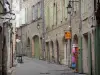 Pézenas - Vieille ville : ruelle pavée bordée de boutiques et de maisons en pierre aux volets verts