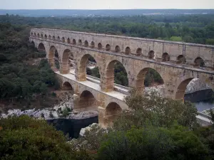 Pont du Gard - Pont-aqueduc romain (monument antique) à trois étages (niveaux) d'arcades (arches) enjambant la rivière Gardon et rives plantées d'arbres ; dans la commune de Vers-Pont-du-Gard