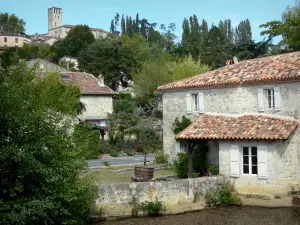 Poudenas - Old mill on the Gélise river, houses of the village, trees and bell tower of the church overlooking the place; in the Pays d'Albret region