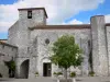 Pujols - La iglesia de San Nicolás, con su campanario, la plaza de San Nicolás y decorado con un árbol y las flores