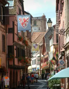 Ribeauvillé - Straat met vlag opknoping, kleurrijke huizen met ramen versierd met bloemen en zet de Slagers (oude belfort) op de achtergrond