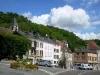 La Roche-Guyon - Fontaine et façades de maisons du village, et clocher de l'église Saint-Samson dominant l'ensemble ; nuages dans le ciel bleu