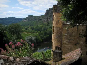 La Roque-Gageac - Roof of a house and a tower of the Tarde manor house with view of the River Dordogne and the trees, the clouds in the sky, in Périgord
