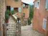 Roussillon - Ruelle en pente avec des maisons de couleur ocre, des fleurs et des plantes