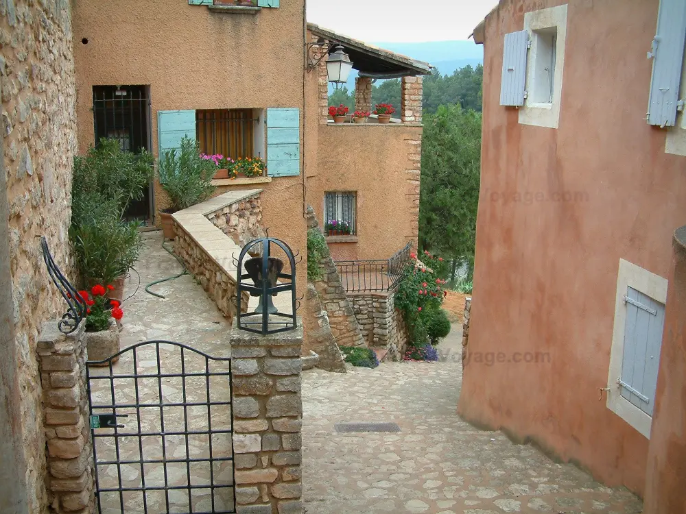 Roussillon - Ruelle en pente avec des maisons de couleur ocre, des fleurs et des plantes