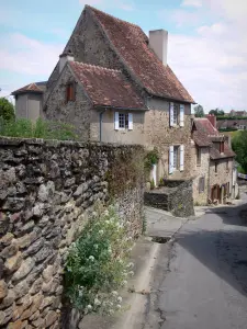 Saint-Benoît-du-Sault - Sloping street and houses of the village, stone wall in foreground