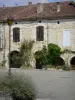 Saint-Clar - Platz République (Platz mit Arkaden): Arkadenhäuser geschmückt mit Blumen und Kletterpflanzen, Strassenlaterne und Lavendel