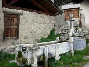 Saint-Véran - Fontaine en bois de Pierre Belle et maisons du village montagnard  ; dans le Parc Naturel Régional du Queyras