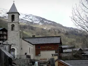 Saint-Véran - Bell tower of the Protestant temple (reformed church), houses of the mountain village and mountain dotted with snow