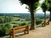 Sainte-Suzanne - Spazierweg Poterne, geschmückt mit Sitzbänken und Bäumen, mit Blick auf die grünende Landschaft