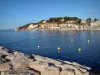 Sanary-sur-Mer - Cliffs, the Mediterranean Sea with yellow buoys, lighthouse, boats and sailboats in the port, pine trees and houses of the seaside resort