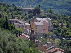 Saorge - Bell tower of the Pénitents Noirs chapel (Saint-Claude chapel), houses, trees and Saorge monastry (former Franciscan convent) in background