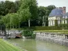 Schloss von Courances - Wassergräben, Beete des französischen Gartens, Nebengebäude und Bäume des Schlossparks