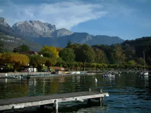 See von Annecy - Ponton aus Holz, See, Boote, Bäumen mit Farben des Herbstes und Berge