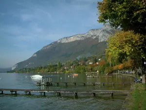 See von Annecy - See, Pontons aus Holz, Boote, Ufer, Bäume mit Farben des Herbstes, Häuser, Waldes und Berg