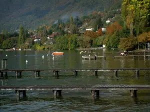 See von Annecy - See mit Ponton aus Holz, Schiff und Bojen, Häuser, Bäume und Wald im Herbst