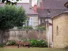 Semur-en-Brionnais - Jardin agrémenté d'un banc, d'un arbre et de fleurs, collégiale Saint-Hilaire (église) et maisons du village ; dans le Brionnais