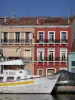 Sète - Houses with colourful facades, flying gull, boat moored to the quay, canal