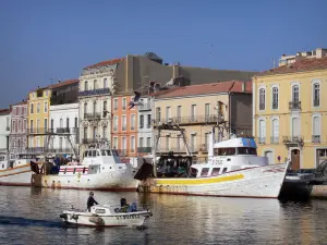 Sète - Boat navigating the canal, fishing boats moored to the quay, houses (some with colourful facades), flying gulls