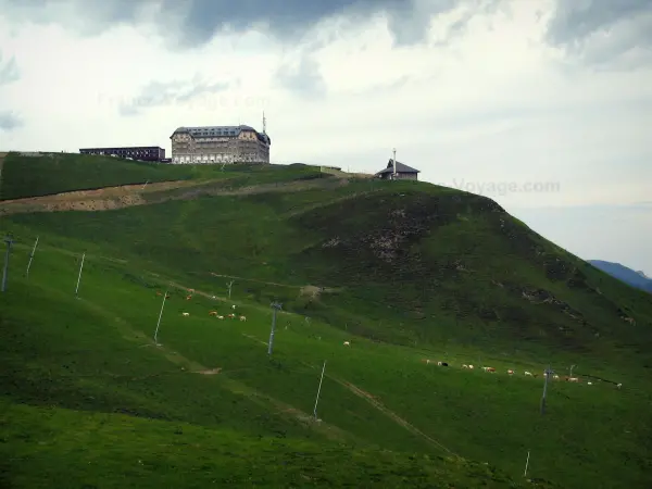 Superbagnères - Edifici, cappella e impianti di risalita della stazione sciistica, e le mucche nei pascoli dei Pirenei