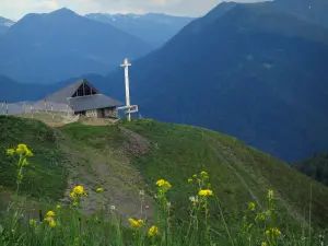 Superbagnères - Erba alta e fiori di campo in primo piano, la cappella in stile moderno della stazione sciistica e le montagne dei Pirenei