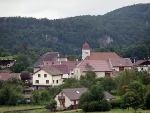 Syam - Kirchturm der Kirche und Häuser der Ortschaft, Bäume und Wald